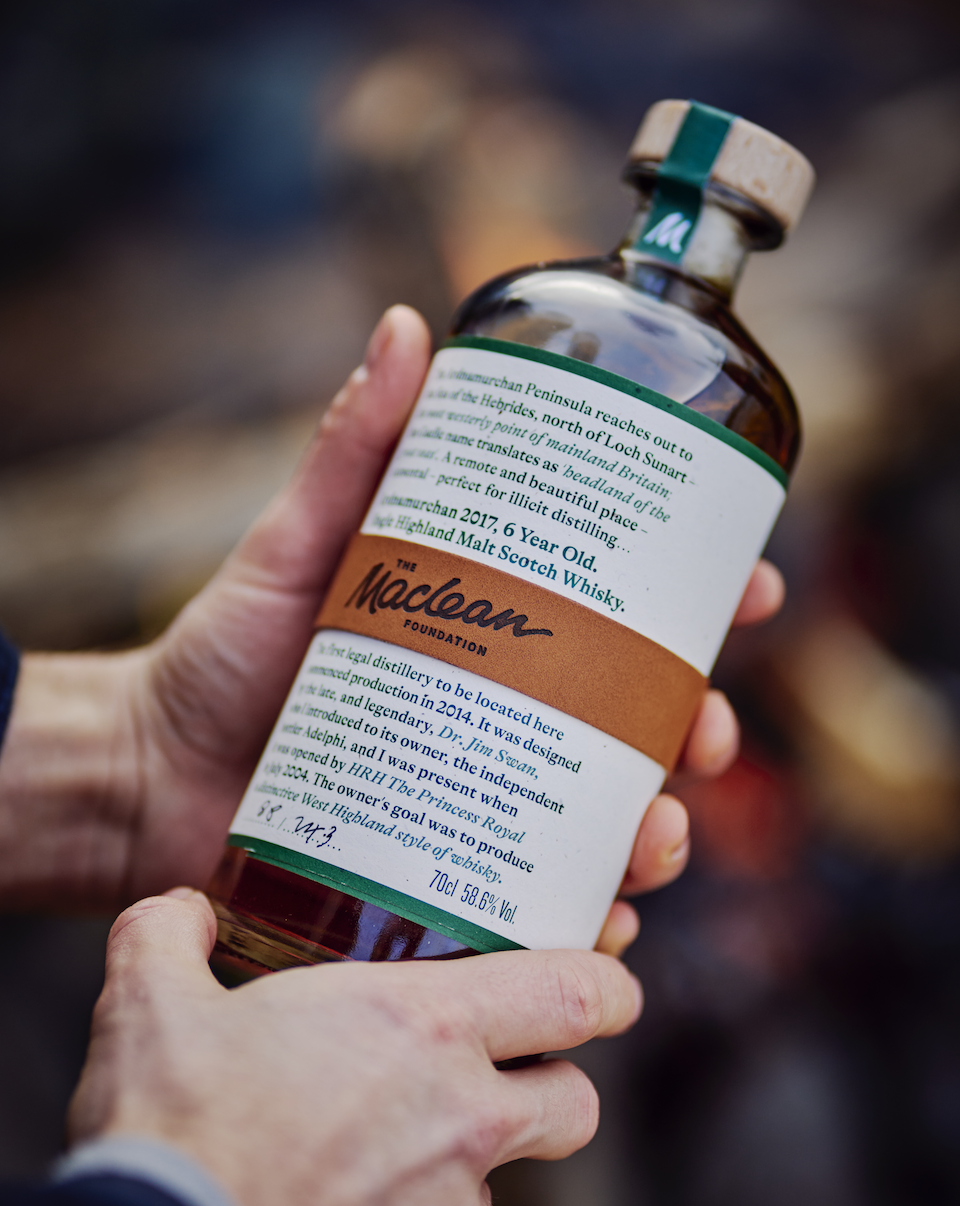 Two hands holding a bottle of whisky