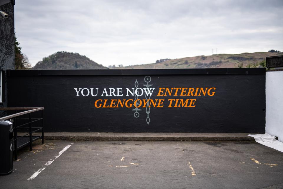 The gate at Glengoyne distillery with the text "You are now entering Glengoyne time" painted on it in large lettering