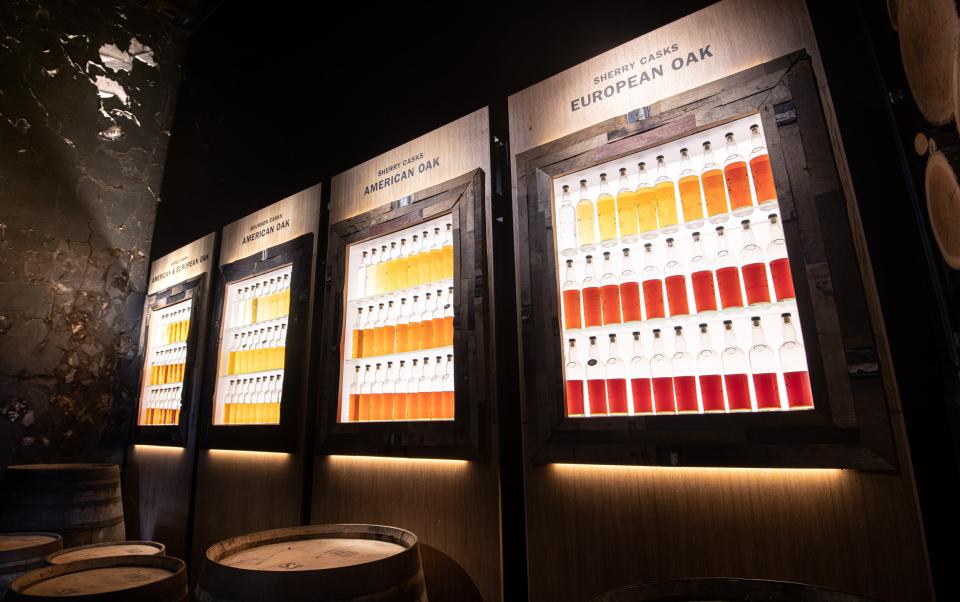 A backlit wall of bottles showing the various stages of maturation