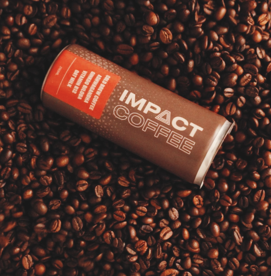 A can of Impact Coffee on a background of coffee beans.